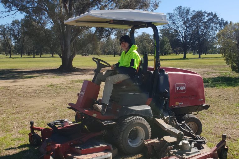 Luke driving a ride on mower at the gold course