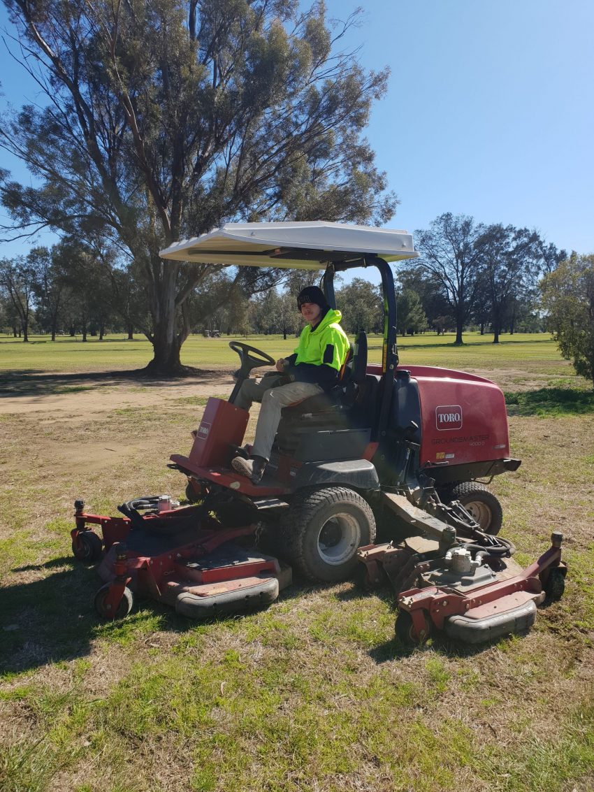 Luke driving a ride on mower at the gold course