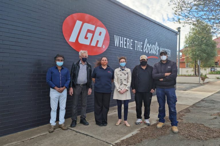 Six people stand outside the new IGA store in Narranderra