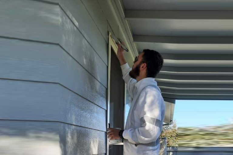 Reece at work painting a grey residential house