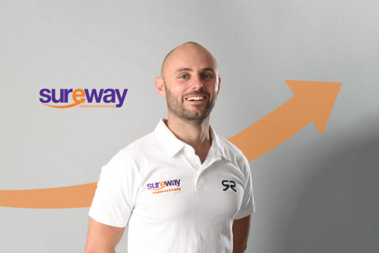 Scott Reardon stands in front of a grey background with an orange arrow going forward.